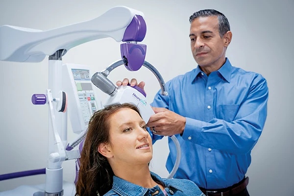 Clinician positioning the NeuroStar treatment coil on a patient’s head