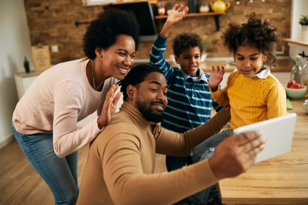 Parents and children smiling together while taking a photo on a tablet