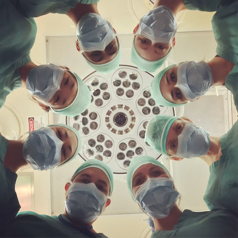 Medical team in masks looking down beneath a treatment light